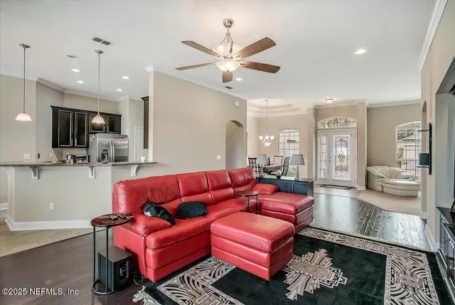 a living room with furniture kitchen view and a wooden floor