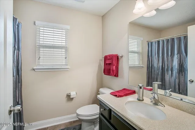 a view of a white house with a yard plants and large tree