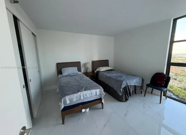 a bedroom with two beds and chair