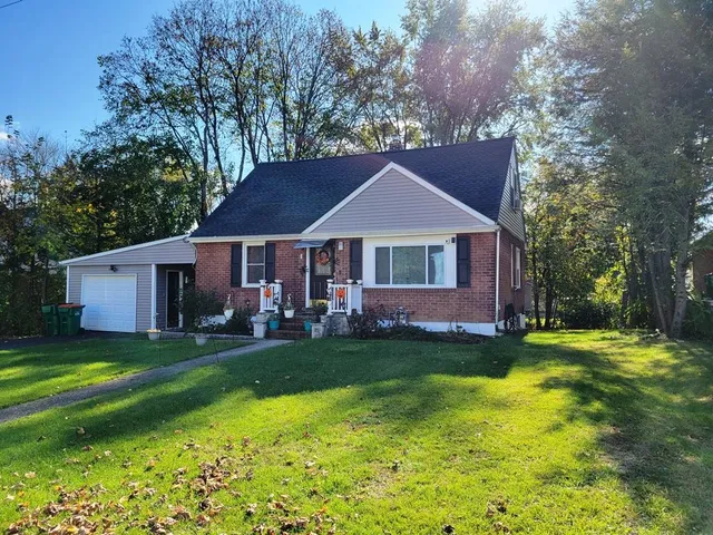a front view of a house with a garden and trees