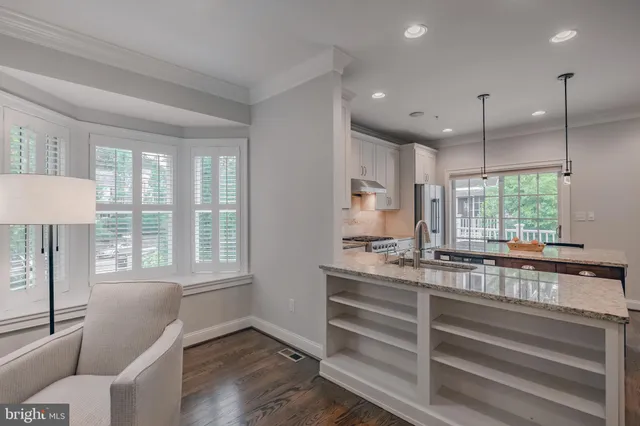 a kitchen with granite countertop a stove a sink a dining table and chairs