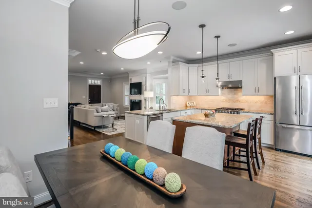 a large white kitchen with granite countertop a sink and dishwasher a stove top oven with wooden floor