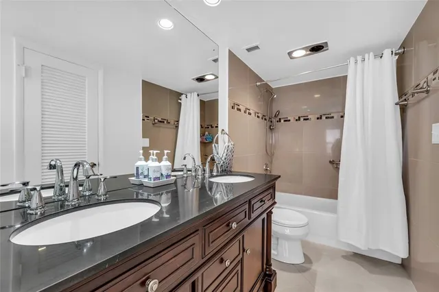 a bathroom with a granite countertop sink a toilet a mirror and shower
