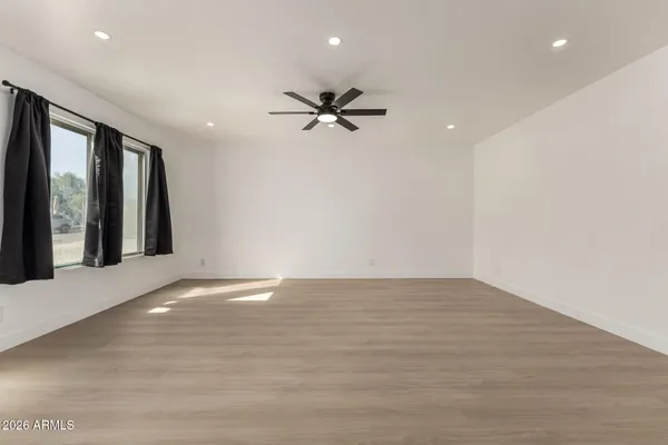 a view of an empty room with chandelier fan and windows