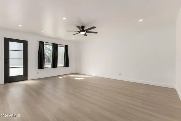 a view of an empty room with window and wooden floor