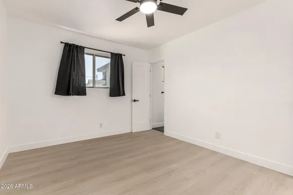 an empty room with window and ceiling fan
