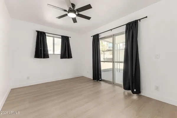 a view of empty room with wooden floor and fan