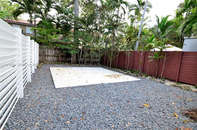 a view of a backyard with wooden fence and a large tree