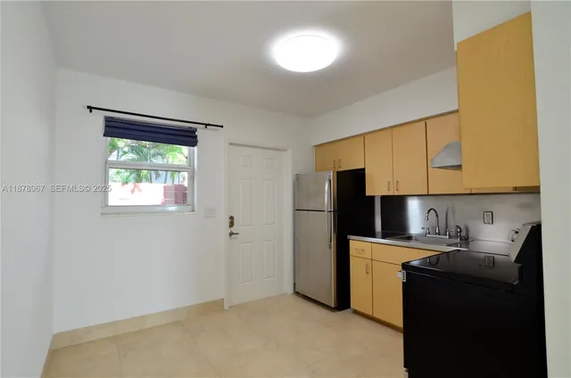 a kitchen with a refrigerator a sink cabinets and a window