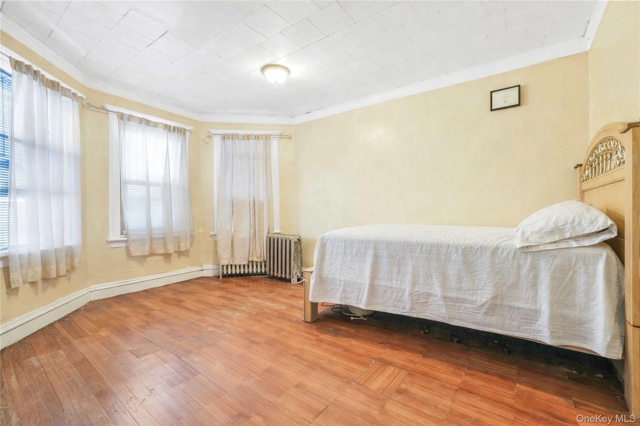 96-12 34th Avenue Queens, NY 11368 - Photo 11 of 35 a bedroom with a bed and a window