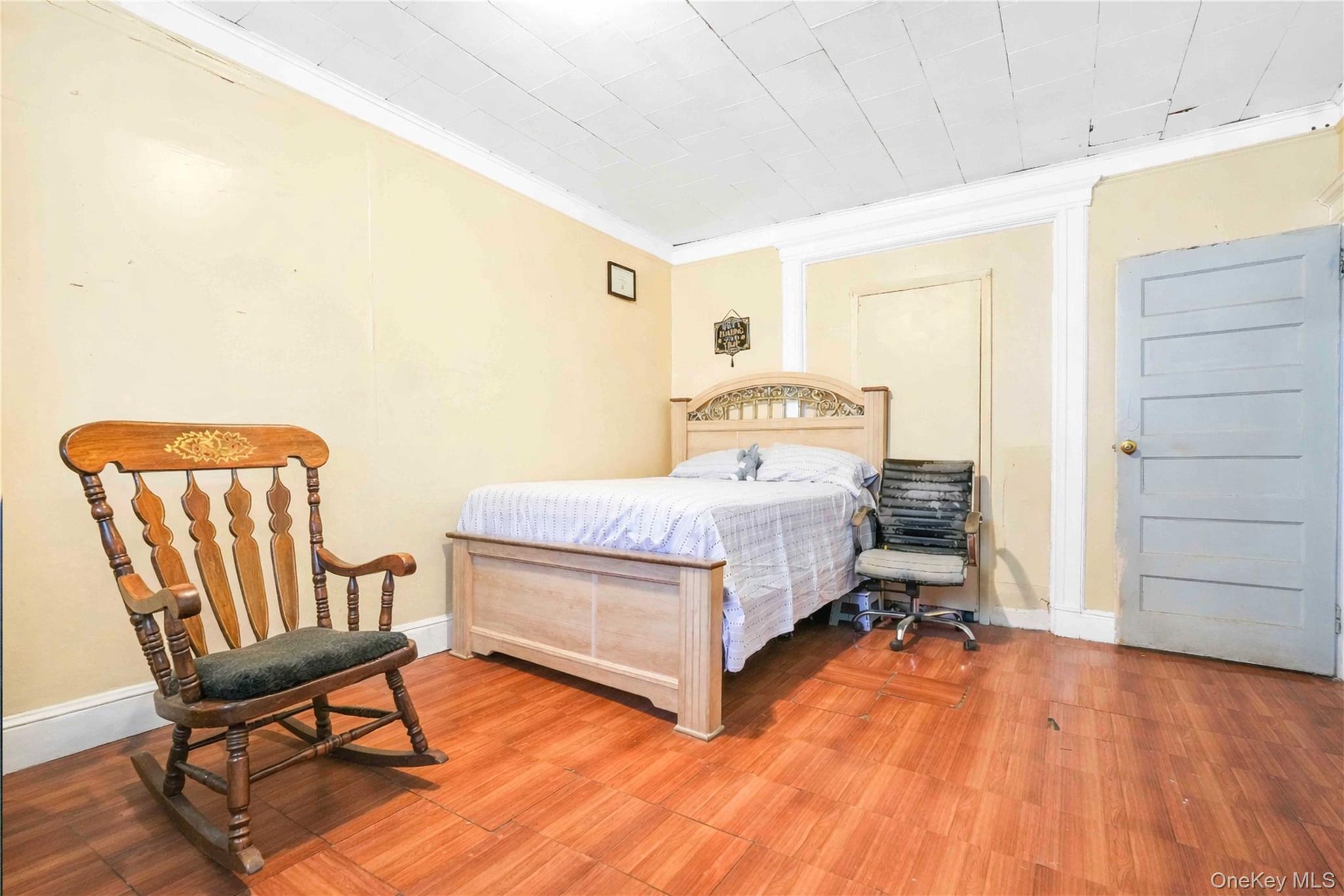 96-12 34th Avenue Queens, NY 11368 - Photo 13 of 35 a bedroom with a bed and a chair