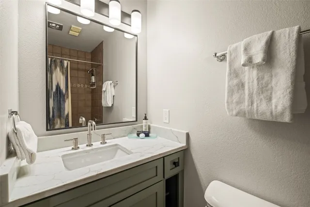 a bathroom with a granite countertop sink mirror and toilet