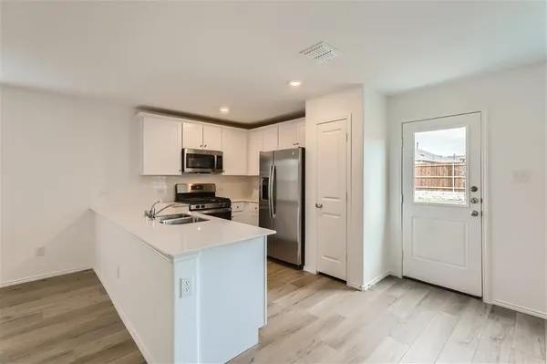 a view of a kitchen with wooden floor and stainless steel appliances
