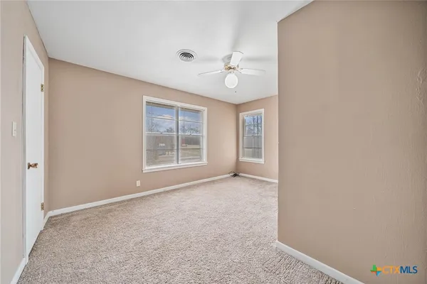 an empty room with windows and fan