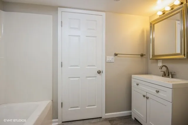 a bathroom with a granite countertop sink and mirror with bathtub