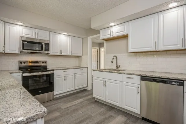 a kitchen with granite countertop white cabinets a sink and stainless steel appliances