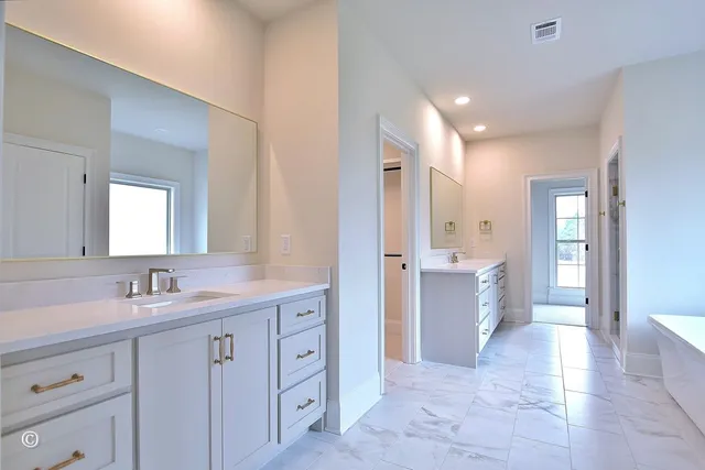 a bathroom with a double vanity sink mirror and a bathtub