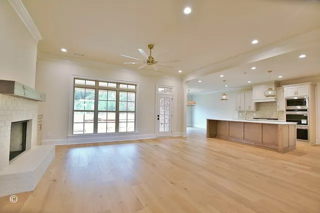 a view of an empty room with wooden floor and a kitchen