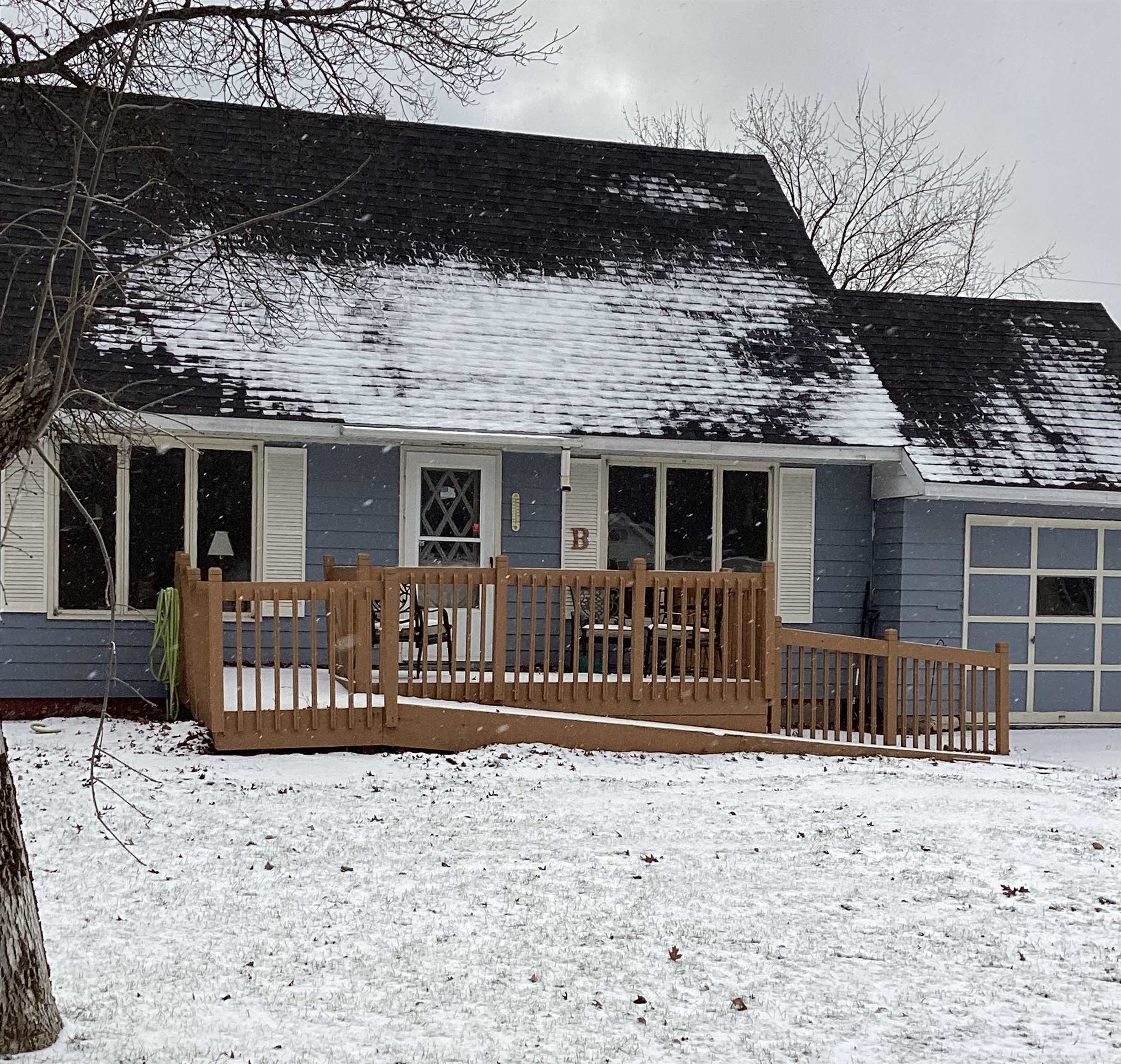 View of front of property with a wooden deck, a garage, and a shingled roof