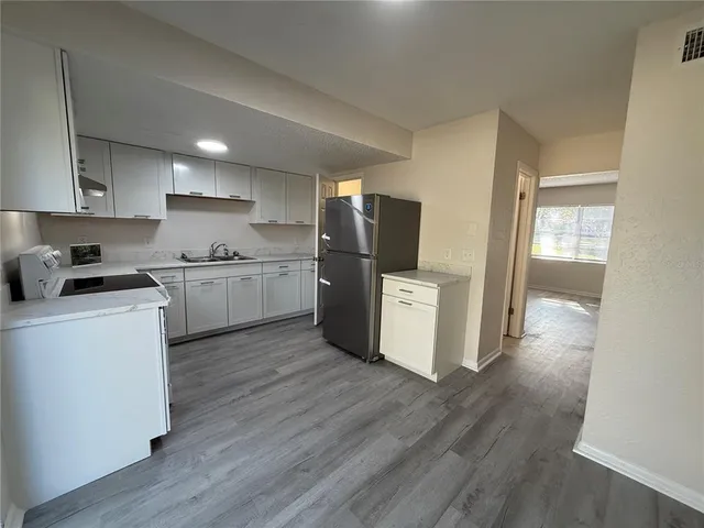 a kitchen with a refrigerator a stove top oven and wooden floor