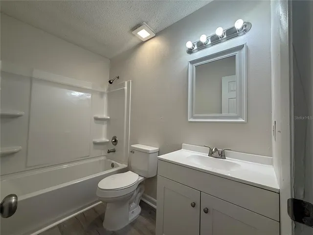 a bathroom with a toilet a sink a mirror a bathtub and vanity
