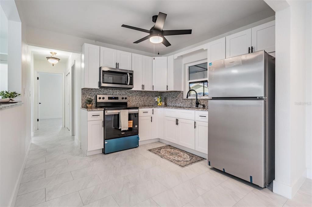 6472 113th Street Seminole, FL 33772 - Photo 16 of 36 a kitchen with stainless steel appliances granite countertop a refrigerator a stove top oven a sink and dishwasher