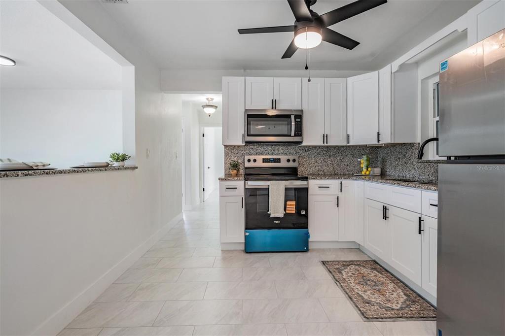 6472 113th Street Seminole, FL 33772 - Photo 18 of 36 a kitchen with stainless steel appliances granite countertop a refrigerator a stove a sink and white cabinets