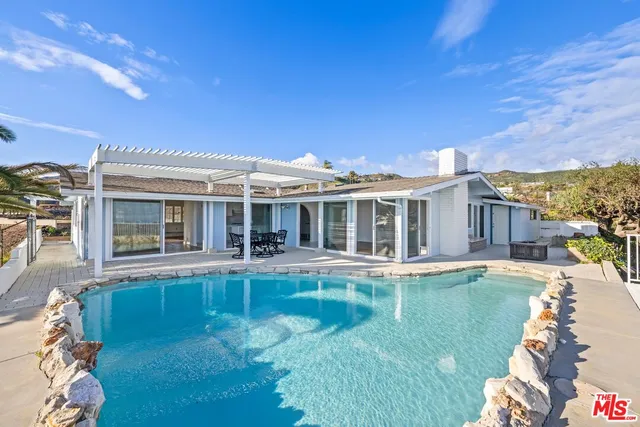 a view of a house with pool fire pit a table and chairs in patio