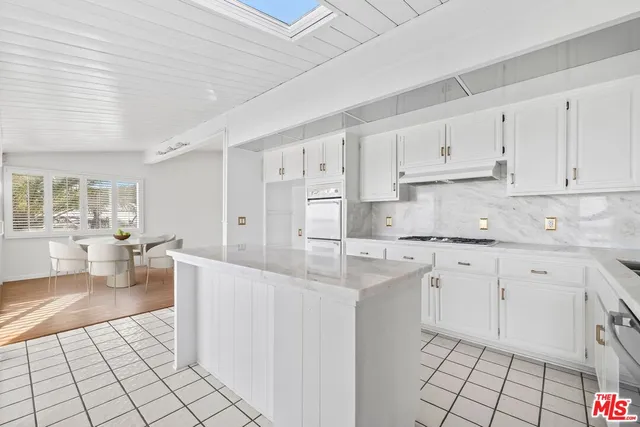 a kitchen with stainless steel appliances white cabinets a sink and a stove