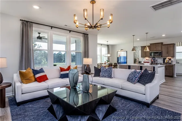 a living room with furniture kitchen view and a chandelier