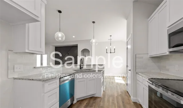 a kitchen with granite countertop a sink a stove and cabinets