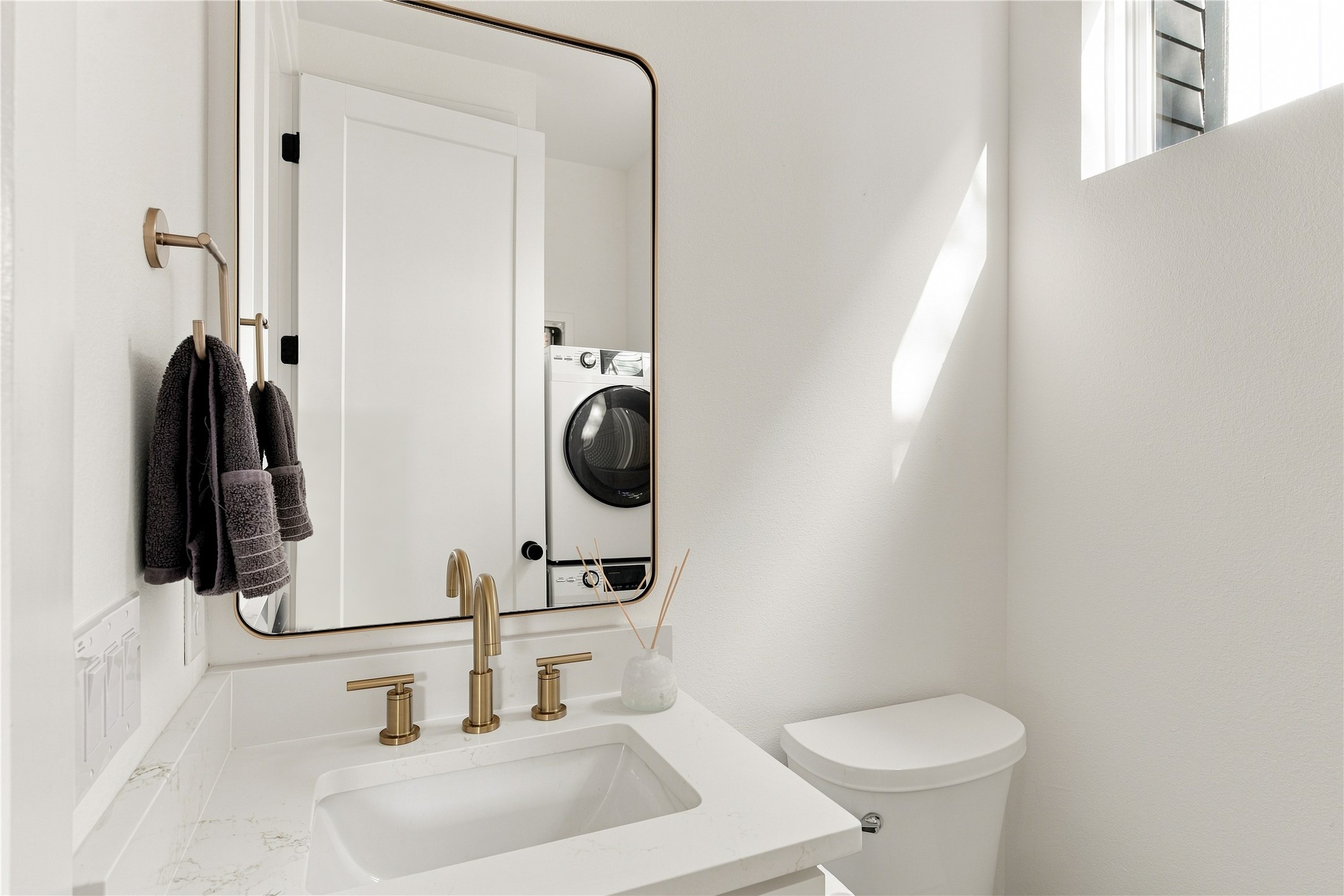 5506 Hudson Street, Unit 2 Austin, TX 78721 - Photo 11 of 24 White stone counters and modern gold fixtures create a refined, minimalist powder room.