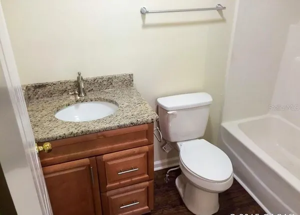 a bathroom with a granite countertop toilet a sink and a bathtub