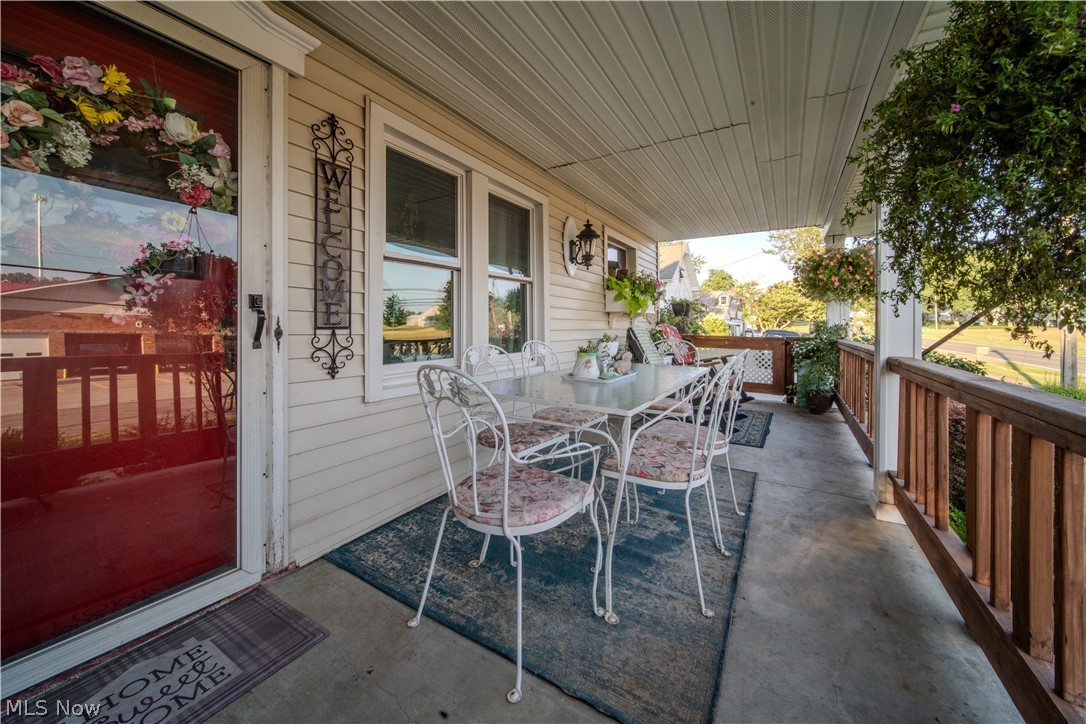 6549 Waterloo Road Atwater, OH 44201 - Photo 5 of 49 Covered porch featuring durable siding, a red entry door, a railing with wood-finish balusters, and an exterior wall light fixture