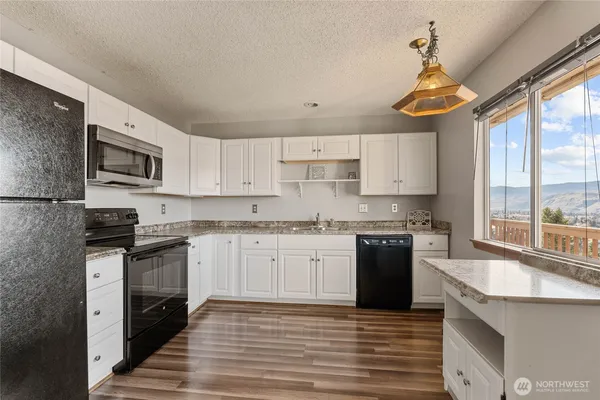 a kitchen with stainless steel appliances granite countertop a stove top oven a sink dishwasher a refrigerator and a microwave oven with wooden floor