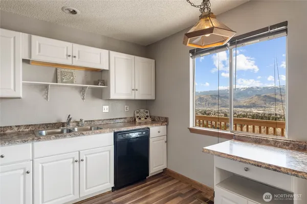 a kitchen with granite countertop a stove a sink and white cabinets with wooden floor