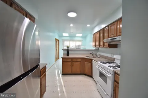 a kitchen with stainless steel appliances granite countertop a sink a stove a refrigerator cabinets and living room view