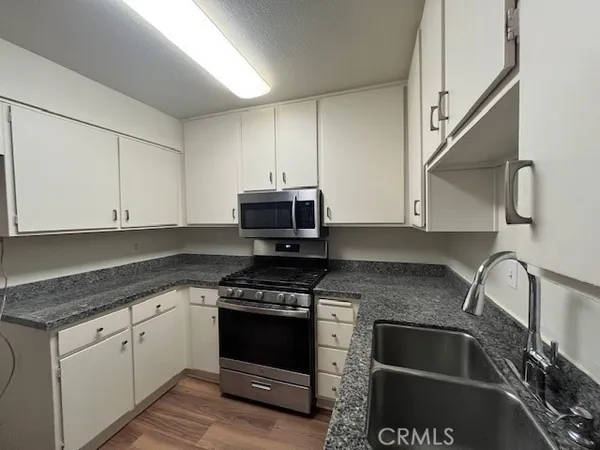 a kitchen with granite countertop a sink stove and white cabinets