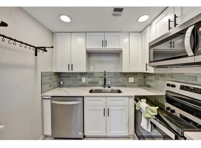 a kitchen with stainless steel appliances a sink stove and cabinets