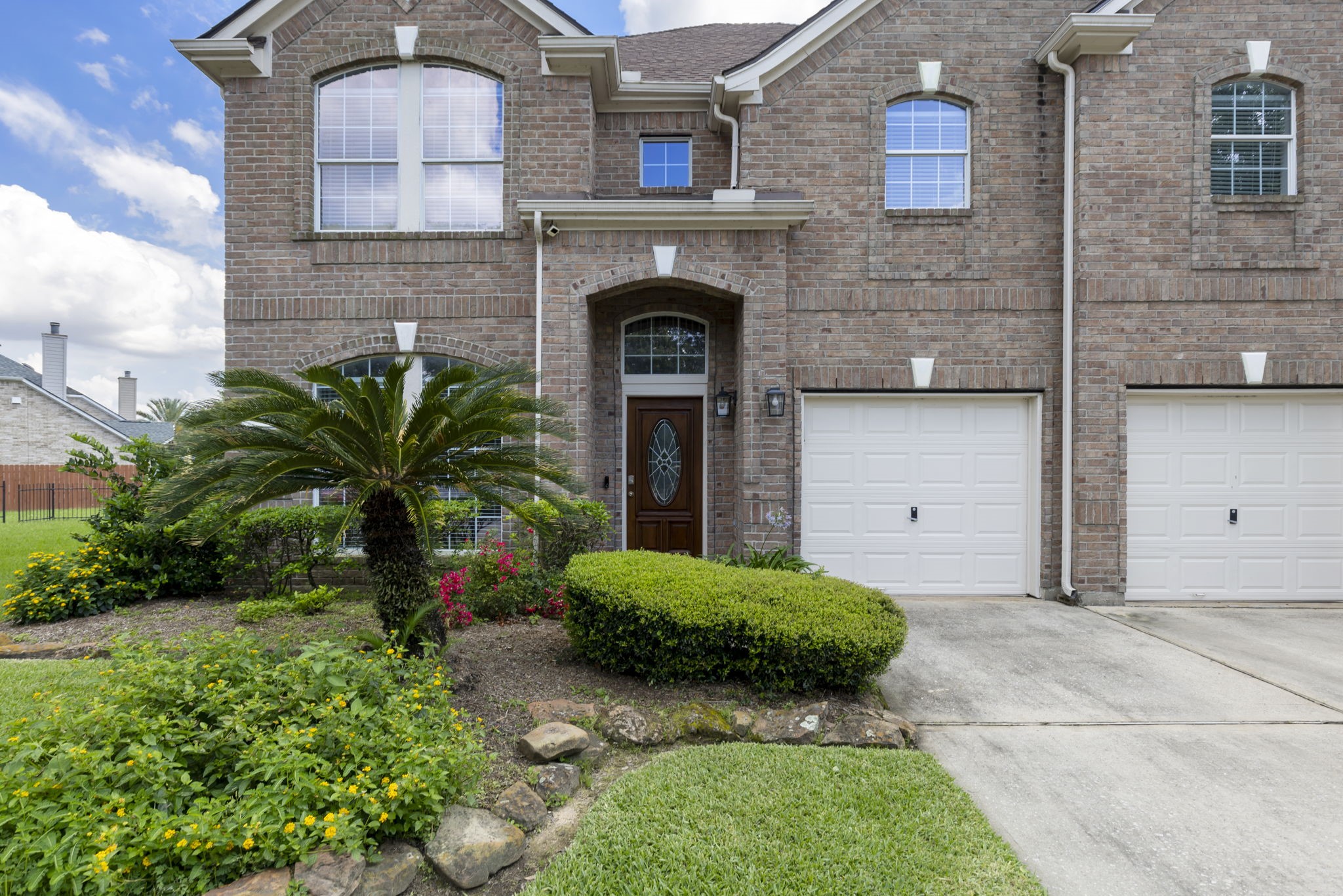 2907 Stemwood Drive Spring, TX 77388 - Photo 2 of 33 Elegant brick exterior with manicured landscaping and mature palm accents create stunning curb appeal for this waterfront two-story home. Features a welcoming covered entry, arched architectural details, and a spacious 3-car garage in a desirable community.