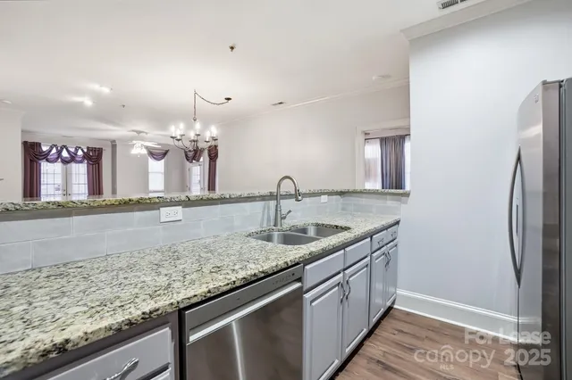 a kitchen with granite countertop a sink and a wooden floor