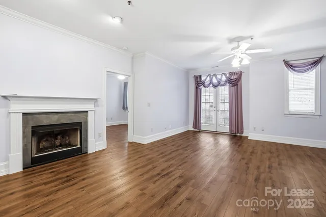 a view of an empty room with wooden floor fireplace and a window
