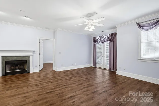 a view of an empty room with wooden floor fireplace and a window