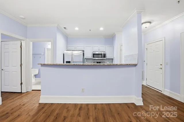 a large kitchen with stainless steel appliances granite countertop a refrigerator and a microwave