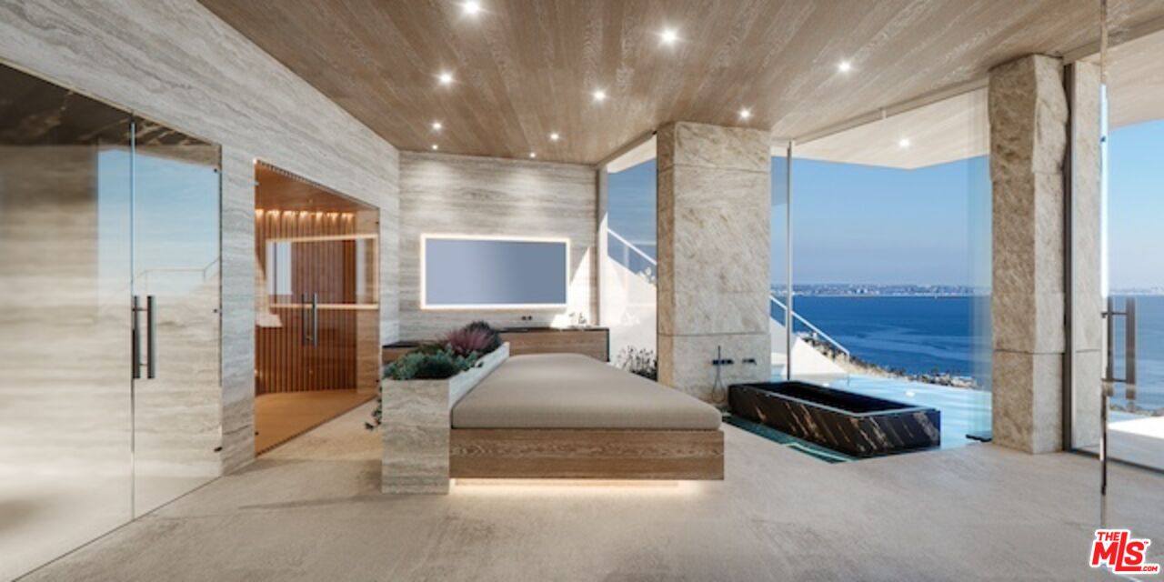 5024 Carbon Beach Terrace Malibu, CA 90265 - Photo 30 of 35 a spacious bedroom with a bed a couch and a chandelier