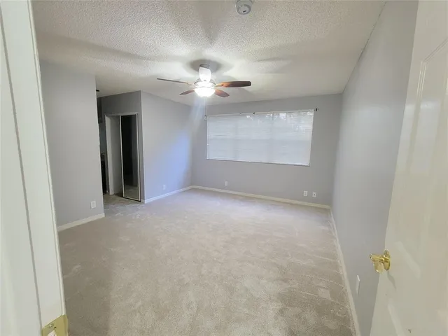 an empty room with a chandelier fan and windows