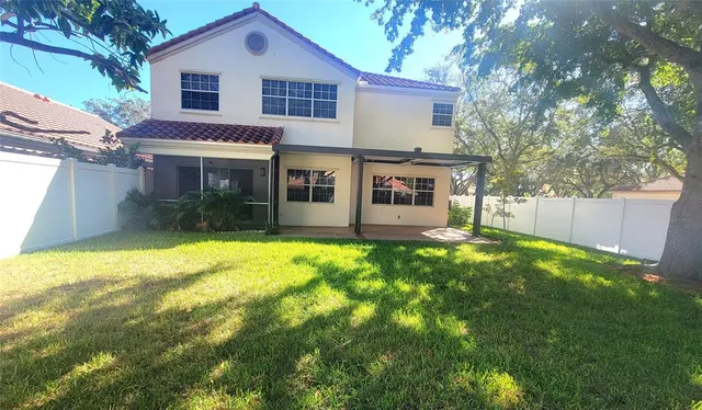 a view of a house with a backyard and a tree