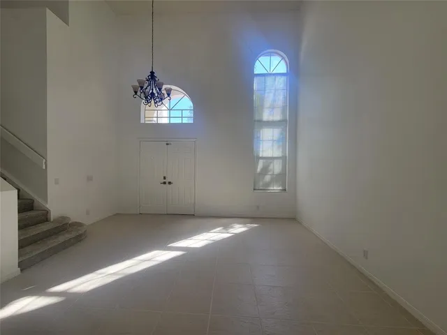 an empty room with windows and chandelier fan
