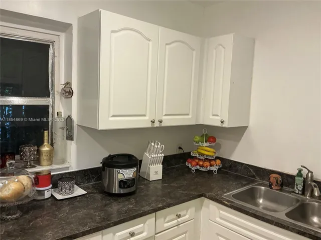a kitchen with white cabinets and sink