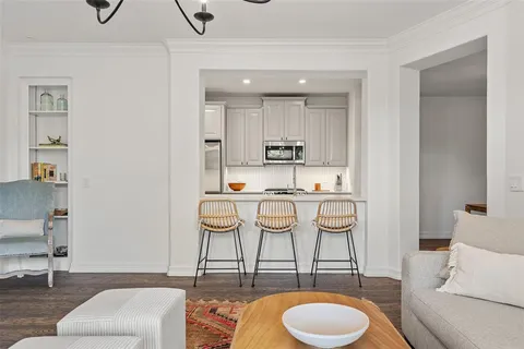 a living room with stainless steel appliances kitchen island granite countertop a dining table and chairs with wooden floor